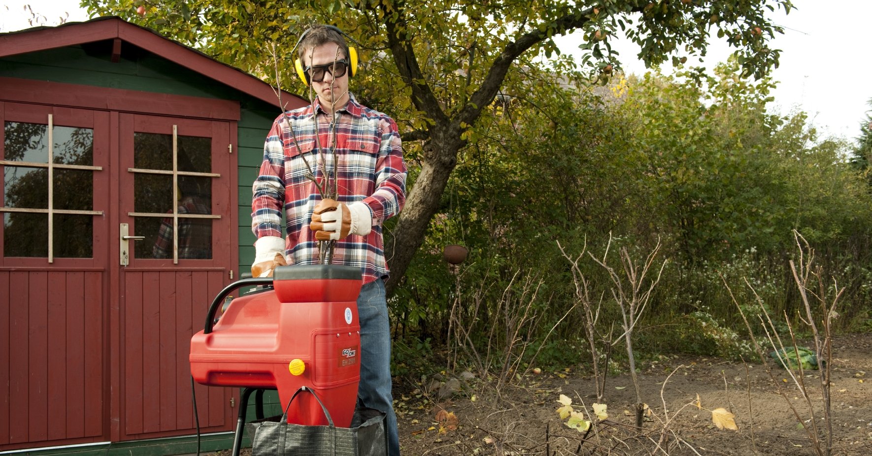 En man hackar trädgårdsavfall i små bitar.